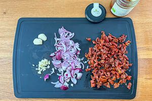 Knoblauch, Zwiebel und getrocknete Tomaten vorbereiten
