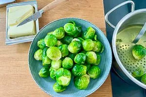 Rosenkohl mit einem Schaumlöffel aus dem Kochtopf schöpfen