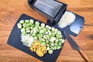 Zwiebeln, Rosenkohl, Kartoffeln und Parmesan für die Suppe vorbereiten