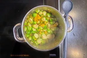 Rosenkohl zu den Zwiebeln und Kartoffelwürfeln in den Topf geben