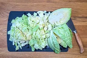 Äußere Blätter und Strunk vom Wirsing entfernen, vierteln und in Streifen schneiden