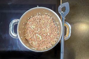 Zwiebeln und Knoblauch zum Hackfleisch geben und anbraten