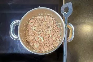 Zwiebeln und Knoblauch zum Hackfleisch geben und anbraten