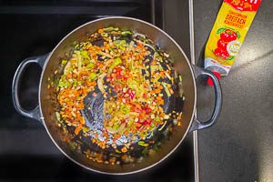 Tomatenmark zum Röstgemüse hinzugeben