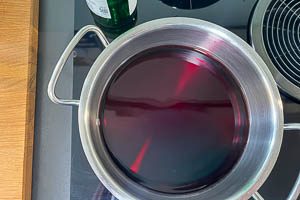 Rotwein und Rum in einen großen Topf gießen