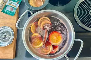 Wein, Orangenscheiben und Gewürze im Topf erhitzen