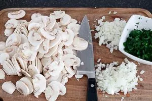 Champignons in Scheiben schneiden, Zwiebeln würfeln und Petersilie hacken