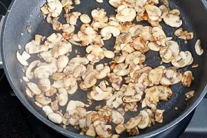 Pilze zu den Zwiebeln geben und scharf anbraten