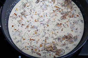 Sahne, Milch, Thymian und Brühe zu den Champignons geben und köcheln lassen. Mit Salz und Pfeffer würzen und nach Belieben mit Speisestärke eindicken