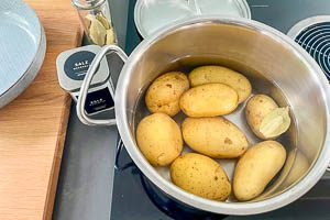 Kartoffeln in einen Topf mit kaltem Wasser und einem Lorbeerblatt geben