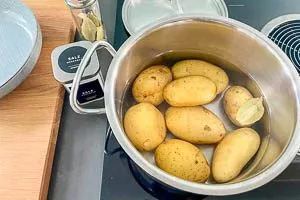 Kartoffeln in einen Topf mit kaltem Wasser und einem Lorbeerblatt geben