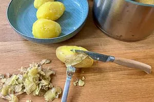 Mit Gabel und Messer die Kartoffeln pellen und die dunklen Stellen wegschneiden