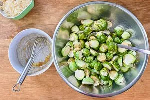 Knoblauch und Marinade mit Rosenkohl vermengen