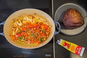 Tomatenmark zum angebratenen Gemüse geben