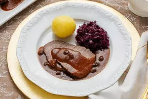 Sauerbraten warm mit Bratensoße, Kartoffelknödeln und Rotkohl servieren