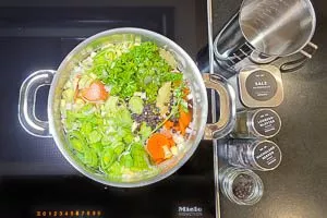 Gemüse zugeben, mit Wasser aufgießen und Salz, Lorbeerblatt, schwarze Pfefferkörner und Wacholderbeeren hinzufügen.