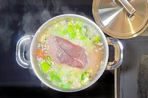 Tafelspitz in die kochende Brühe geben.