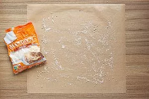 Backpapier mit gemahlenen Mandeln bestreuen.