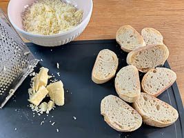 Käse fein reiben und Baguette schneiden und antoasten.