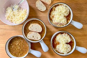 Zwiebelsuppe mit Baguette und Käse bedecken und im Ofen überbacken.