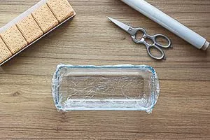 Kastenform mit Frischhaltefolie auskleiden, Butterkekse bereitstellen