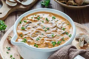 Pilzrahmso&szlig;e mit Petersilie garnieren und warm servieren