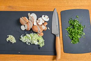 Zwiebeln, Knoblauch, Petersilie und frische Champignons kleinschneiden