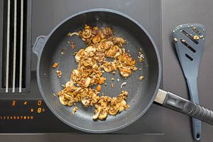 Eingeweichte Pilze und Knoblauchwürfel in die Pfanne geben