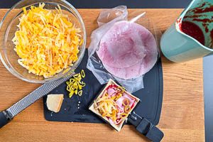 Teig auf der oberen Platte vorbacken und anschließend Tomatensoße, Parmesan, Schinken, Pfefferonen und Käse darauf verteilen.