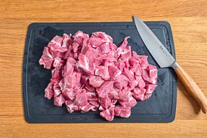 Fleisch in Würfel schneiden.