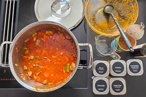 Tomaten, Gemüsebrühe, Gewürze und Fleisch zugeben und köcheln lassen.