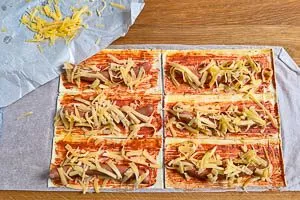 Würstchen und Käse auf jedes Stück Blätterteig geben