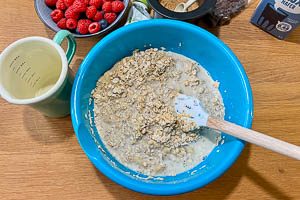 Pflanzenmilch, Bananenbrei, Mandeln, Pflanzenöl und Zucker zu den Haferflocken hinzugeben
