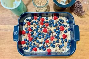 Haferflocken-Masse, restliche Beeren und Topping nach Wahl in die Auflaufform geben