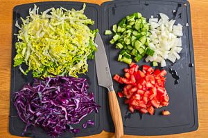 Tomaten, Gurke, Zwiebeln, Romanasalat und Rotkohl in Stücke und Streifen schneiden