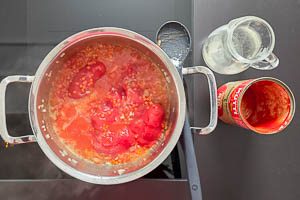 Mit Tomaten und Gemüsebrühe ablöschen.