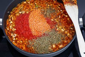 Gem&uuml;se mit Br&uuml;he und st&uuml;ckigen Tomaten abl&ouml;schen und rote Linsen hinzugeben