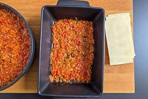 Beim Einschichten der Lasagne mit der Linsenbolognese beginnen