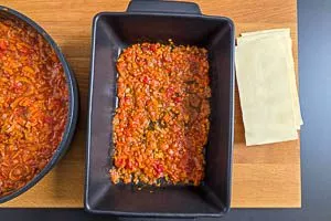 Beim Einschichten der Lasagne mit der Linsenbolognese beginnen