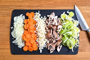 Zwiebeln, Sellerie, Möhren, Lauch und Champignons vorbereiten und schneiden