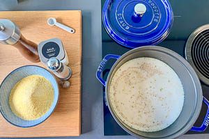 Gemüsebrühe mit Milch und Salz, Pfeffer und Muskatnuss im Topf aufkochen