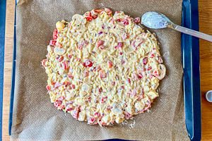 Masse mittig auf das Backblech geben und mit einem Löffel zu einer Pizza formen