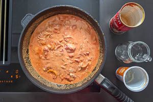 Mit geschälten Tomaten, Gemüsebrühe und Schmand ablöschen.