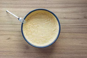 Mit dem Rest des Teiges den Rand einkleiden und mit einer Gabel L&ouml;cher in den Boden stechen