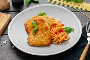 Spaghetti mit Tomatenso&szlig;e und Kalbsschnitzel servieren. Fertig ist deine Piccata Milanese!