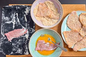 Jedes Schnitzel durch das Ei ziehen und anschließend in die Panade drücken