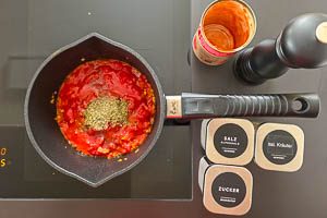 Stückige Tomaten dazugeben und mit Salz, italienischen Kräutern, Pfeffer und Zucker würzen