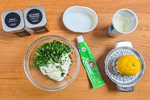 Frischkäse, Schmand, Zitrone und Gewürze mit Bärlauch in einer Schüssel vermengen