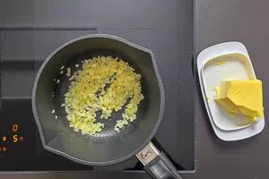 Butter in einem Topf schmelzen und Zwiebelw&uuml;rfel glasig d&uuml;nsten