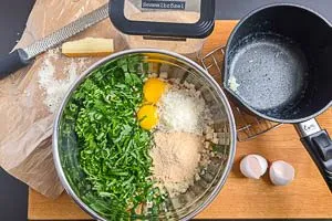 Milch-Masse, Parmesan, Paniermehl, B&auml;rlauch und Eier zu den Br&ouml;tchenw&uuml;rfeln geben